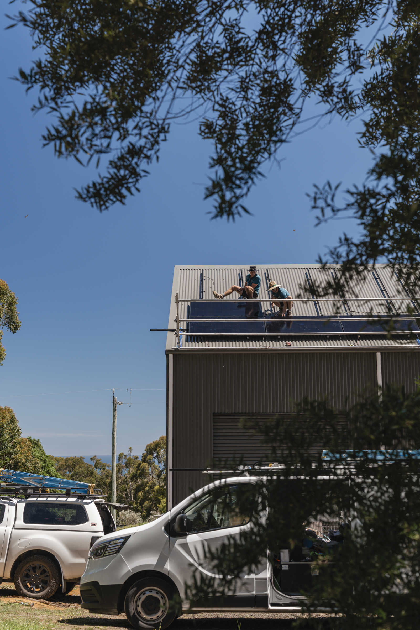 Installers fitting AIKO solar panels to the north-facing shed roof.